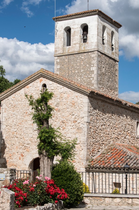se encuentra inmersa en el caserío, del que descuella su maciza torre. Está orientada y consta de planta basilical de única nave a la que se une cabecera semicircular de época moderna