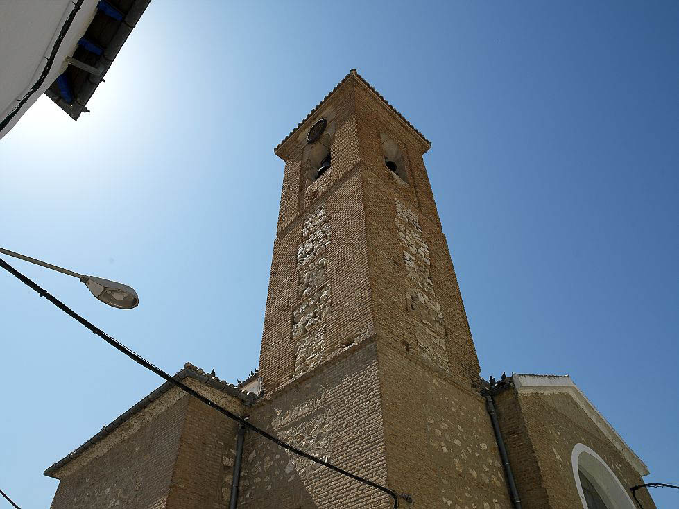 vista de la torre de la iglesia del municipio, de estilo sencillo construida en ladrillo y piedra con un campanario en su parte más alta.