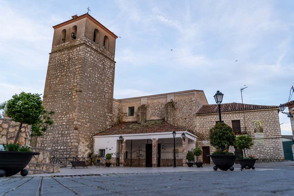 Surroundings of the town square and church. It was burned during the Spanish Civil War and rebuilt in 1951, which explains the mixture of styles in its architecture. Particularly noteworthy are the four Romanesque-style carved heads located at the corners of the tower.
