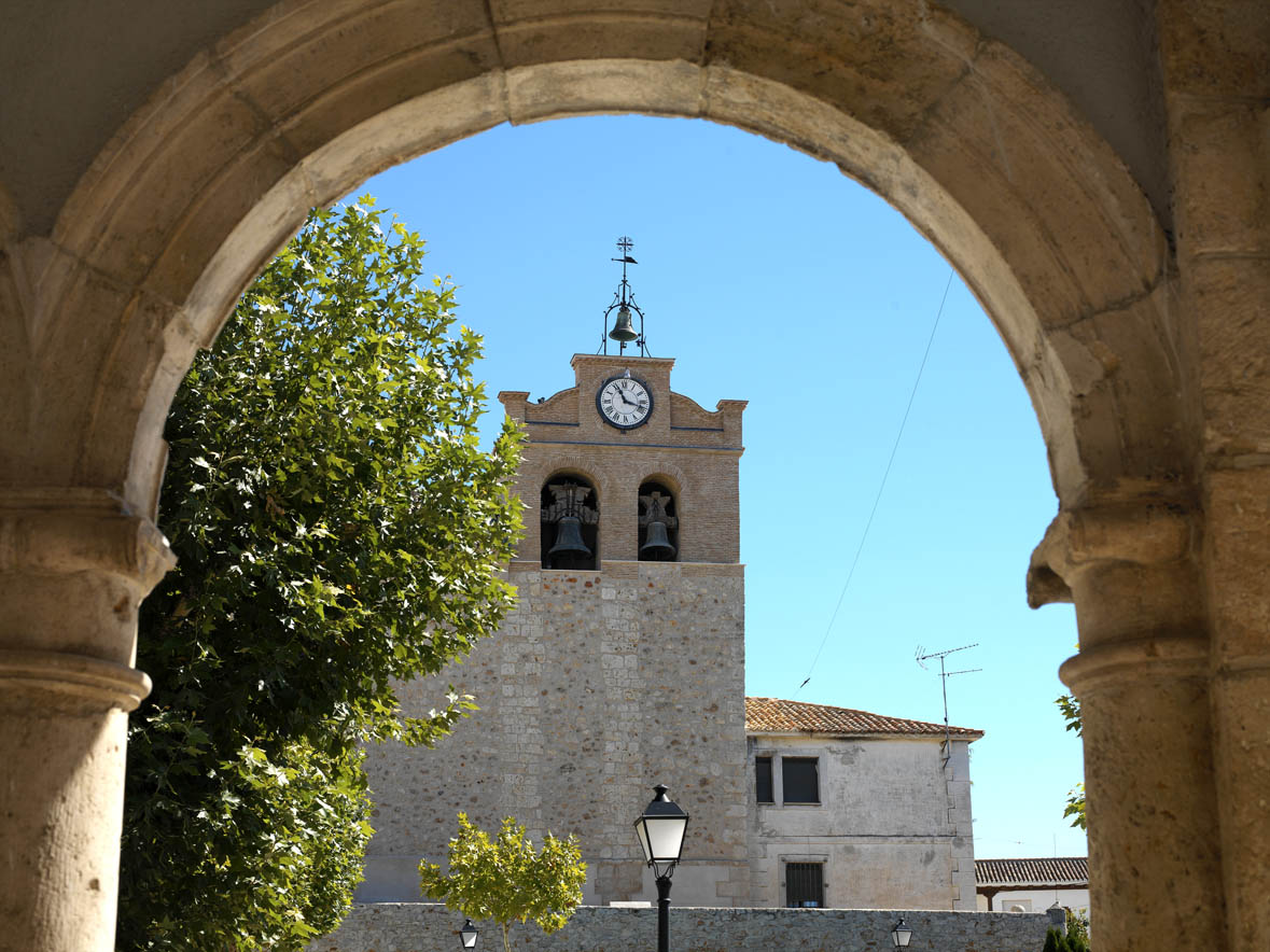 vista a través del arco de la torre-campanario de la monumental iglesia de Estremera, un municipio repleto de plazuelas de fachadas blancas y caserones con ventanas enrejadas.