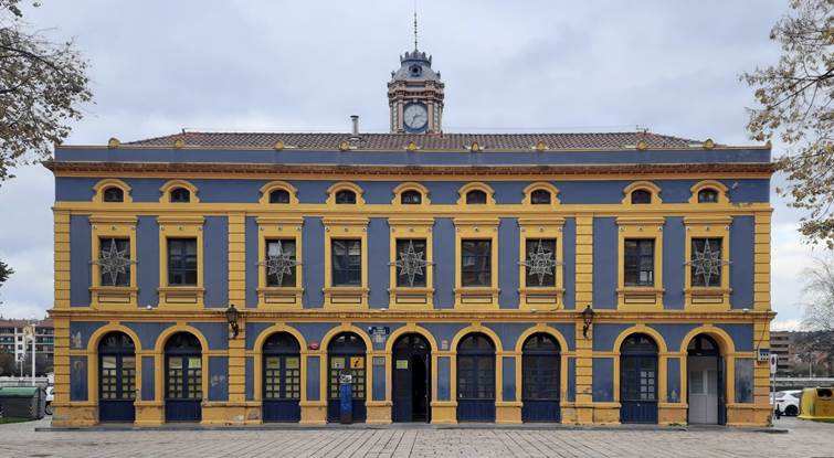 Edificio neoclásico en azul y amarillo, en cuyos arco central es la entrada de la oficina de Turismo.