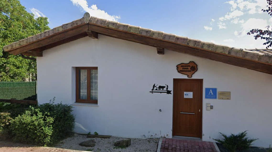 Puerta de madera en fachada blanca con una ventana a la izquierda