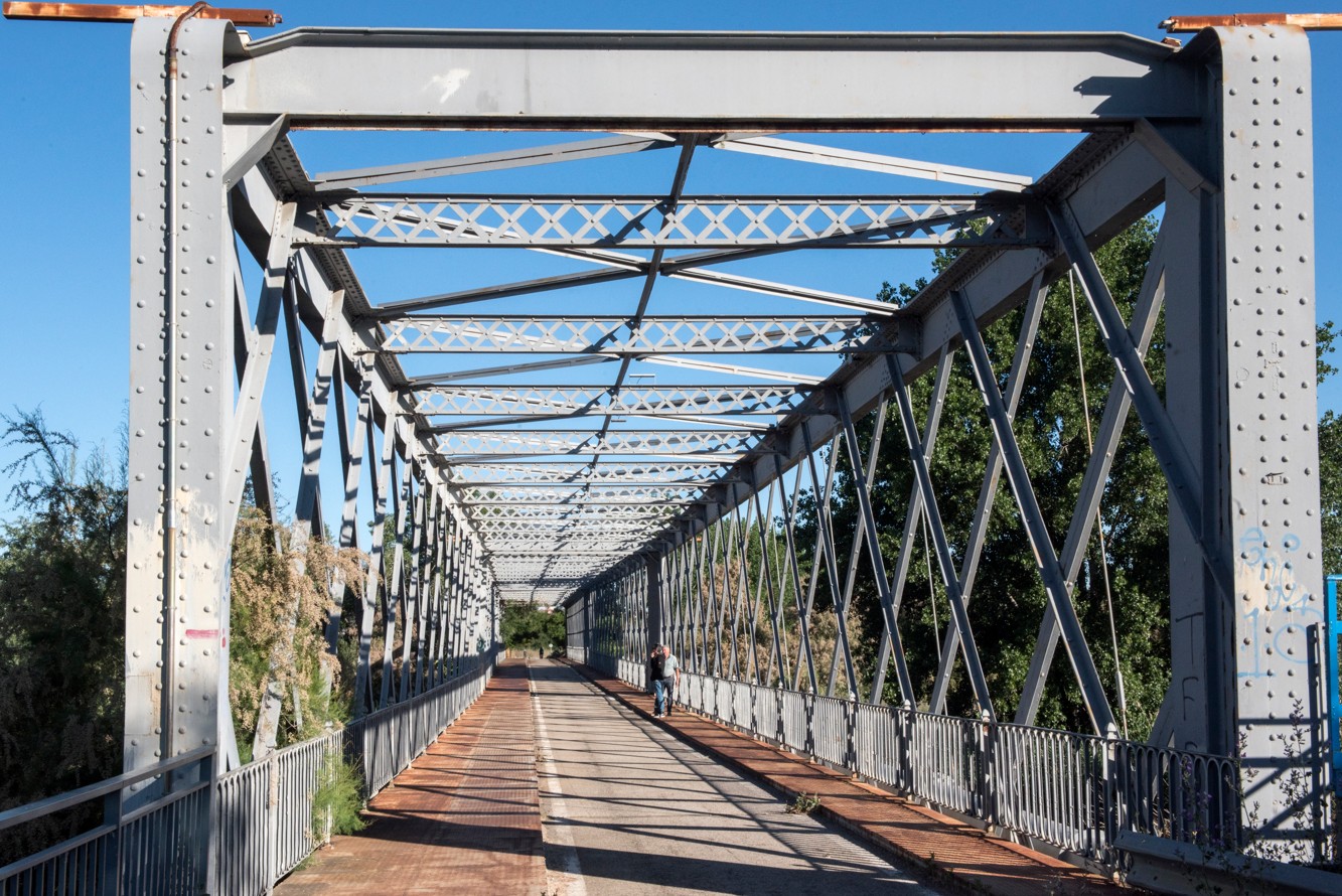 Iron bridge built over the River Tajuña, with three distinct spans, having undergone various refurbishments over the years.