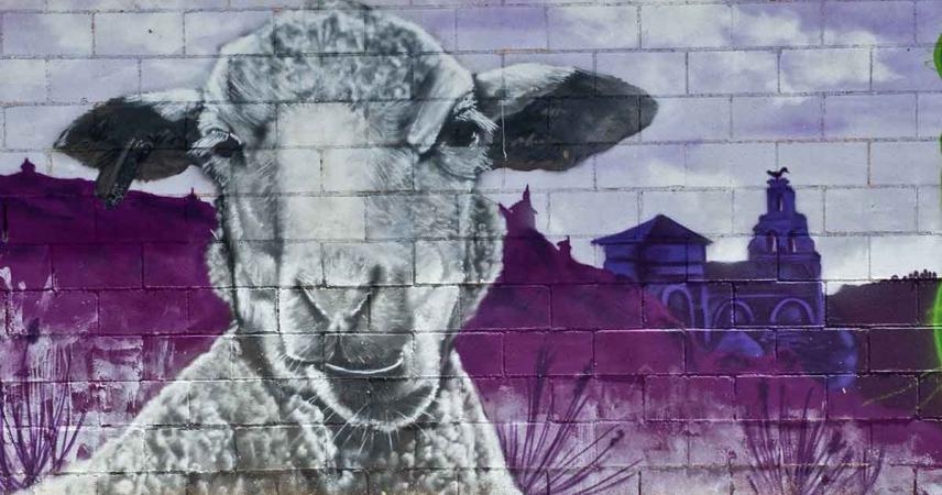 Fresque murale représentant des moutons avec La Torre del Valle en arrière-plan dans des tons violets