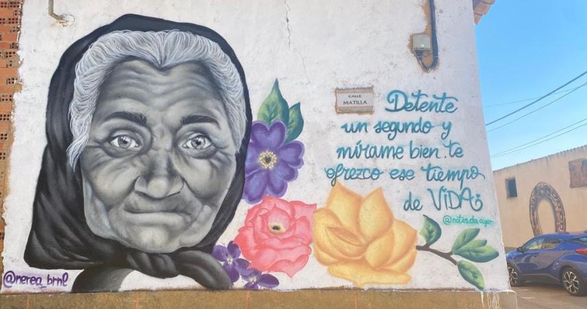 Peinture murale d&#39;une vieille femme en noir et blanc avec des fleurs dans les tons de jaune, rose et violet