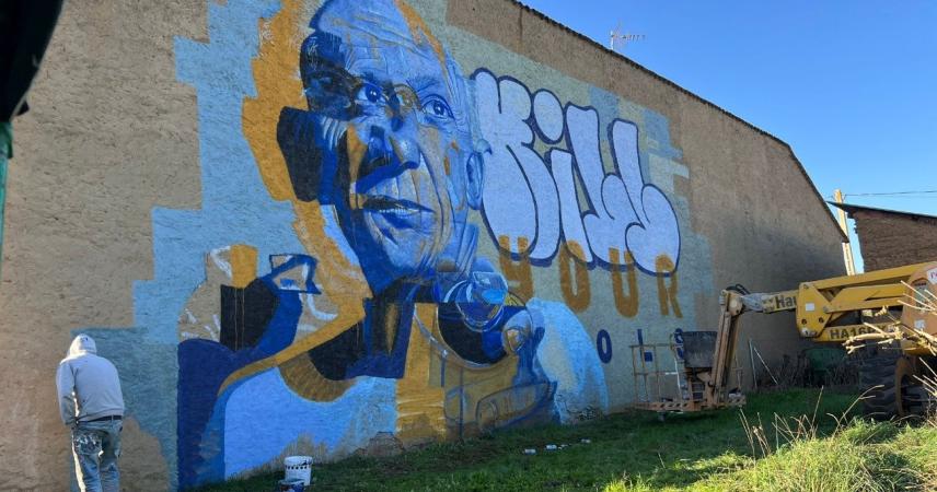 Peinture murale représentant le visage d&#39;un homme dans les tons bleus et jaunes avec le texte « Tuez vos idoles »