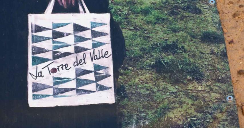 Peinture murale d&#39;une femme dans un pré avec un sac d&#39;El Corte Inglés sur lequel est écrit « La Torre del Valle »