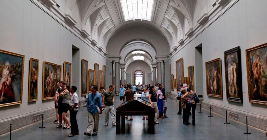 Photographie d'un des couloirs du musée, où l'on peut voir les murs remplis de peintures et de nombreux visiteurs.