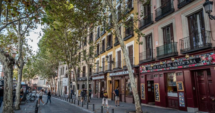 Photo of a street in the neighborhood where you can see several pedestrians and bars.