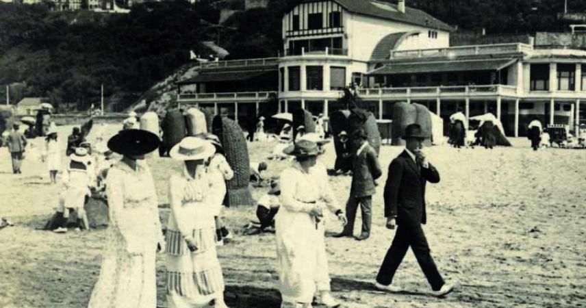 Imagen antigua de un grupo de personas paseando por la playa