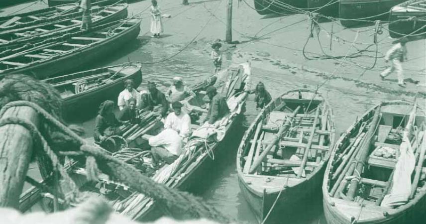 Imagen antigua de un grupo de hombres en una txalupa en el puerto