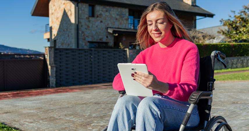 Una chica en silla de ruedas utilizando una tableta digital