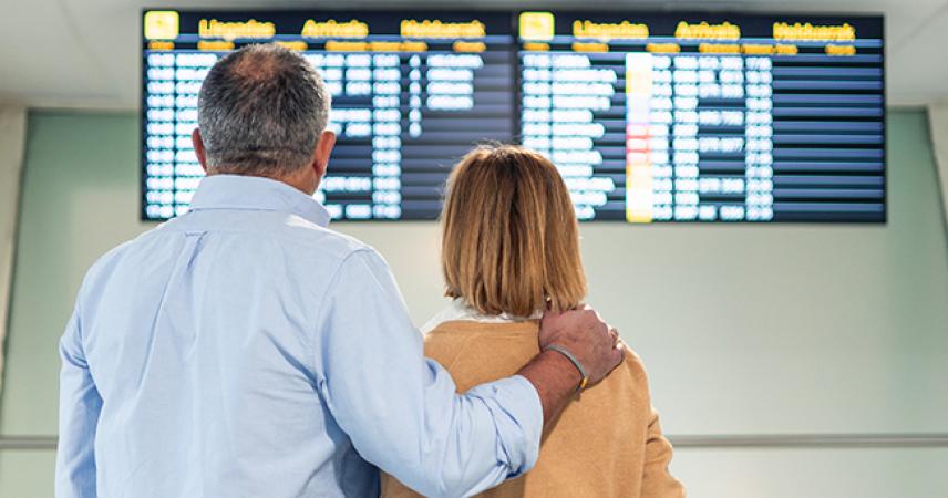 Un matrimonio mirando los horarios de vuelos en la pantalla del aeropuerto
